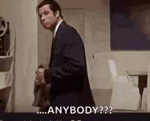 a man in a suit and tie is standing in a room and says `` anybody ? ''
