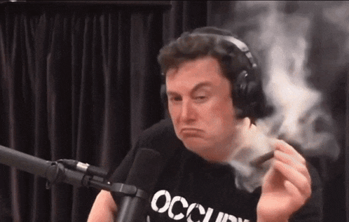 a man wearing headphones is smoking a cigar in front of a microphone while wearing an occupy shirt .