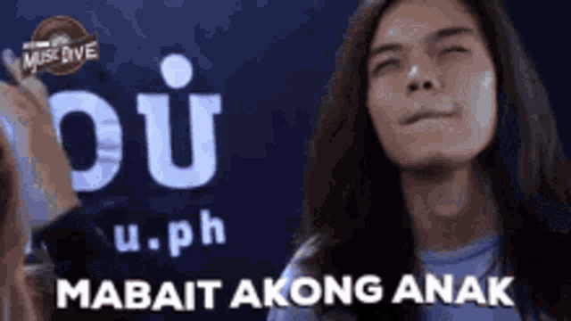 a man with long hair is making a funny face while standing in front of a sign that says u.ph .