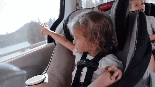 a little girl is sitting in a car seat that says positioning