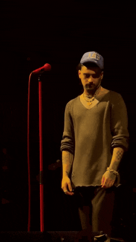 a man singing into a microphone wearing a blue hat that says ' los angeles ' on it