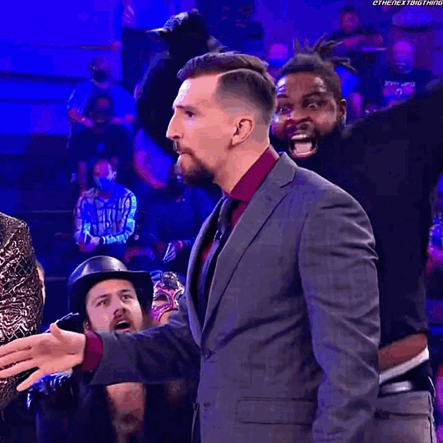 a man in a suit and tie stands in front of a crowd with the hashtag #thenextthing