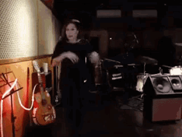 a woman is standing in front of a guitar in a room