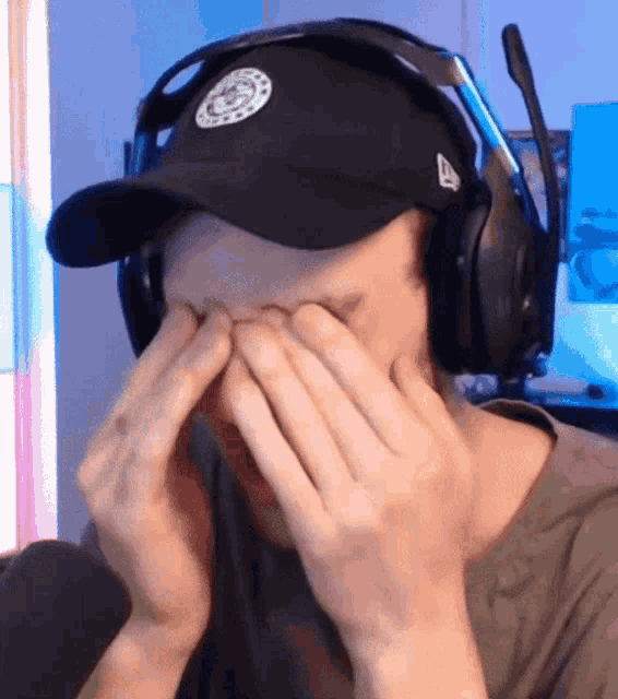 a man wearing a hat and headphones is covering his eyes