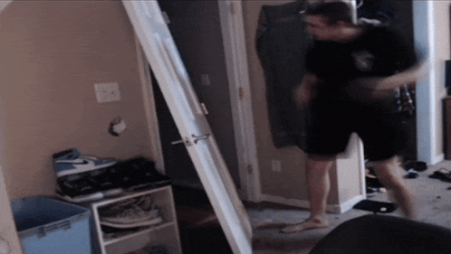 a man in a black shirt and black shorts is standing in a hallway