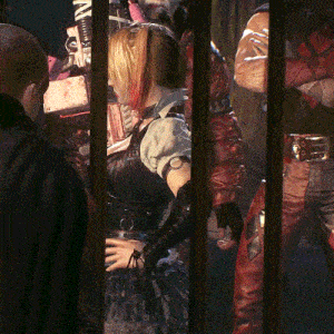a woman in a costume is behind bars with a man in a black jacket