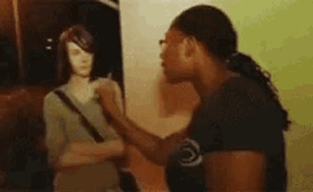 a woman is slapping another woman in the face while standing in front of a mirror .