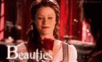 a woman is holding a red rose in her hand and the word beauties is on the bottom of the image .