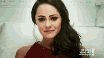 a woman in a red dress is sitting in a hospital bed and looking at the camera .