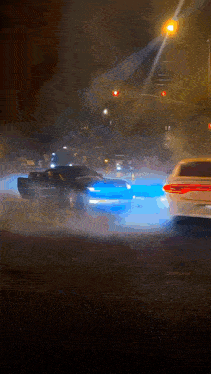 a car driving down a street at night with a red light behind it