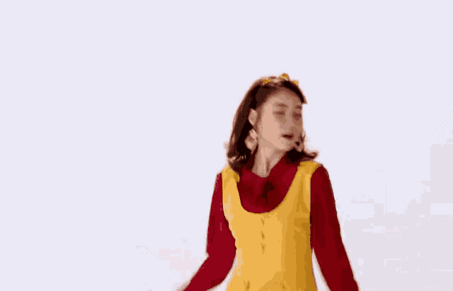 a young woman in a yellow dress and red shirt is dancing .