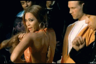 a group of people are standing around a woman in a red dress