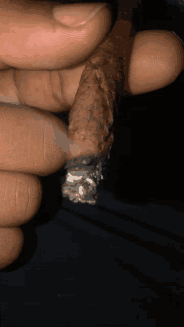 a close up of a person 's hand holding a cigar