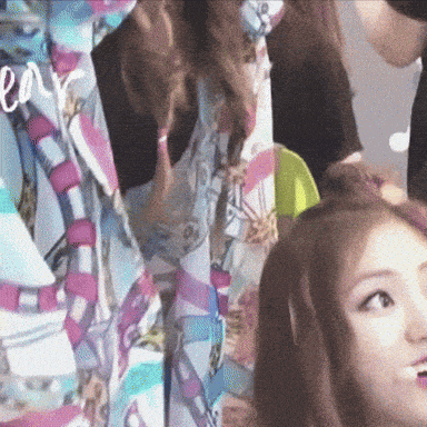 a woman is getting her hair done in front of a colorful curtain with the word love written on it