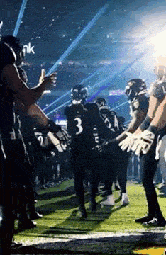 a group of football players are standing on a field in a stadium .