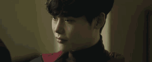 a close up of a young man 's face with a red sweater on .