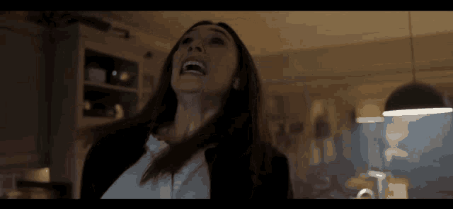 a woman is screaming in a dark room and her hair is blowing in the wind