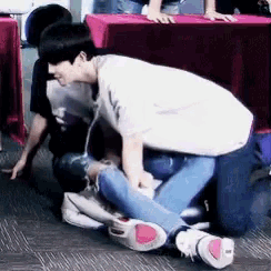 a man in a white shirt is kneeling down next to another man .