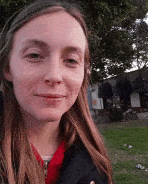 a woman with long hair is smiling in a park