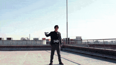 a man is standing on a rooftop with a belt that has the letter x on it