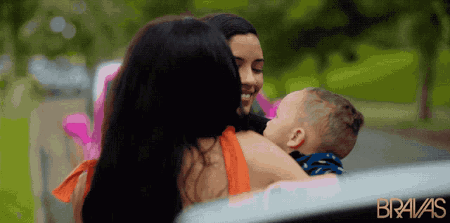 a woman holding a baby in her arms with the word bravas on the bottom