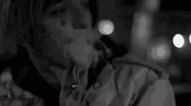 a black and white photo of a person smoking a cigarette in a dark room .