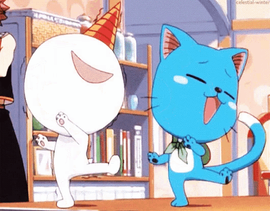 a blue cat is standing next to a white cat wearing a birthday hat