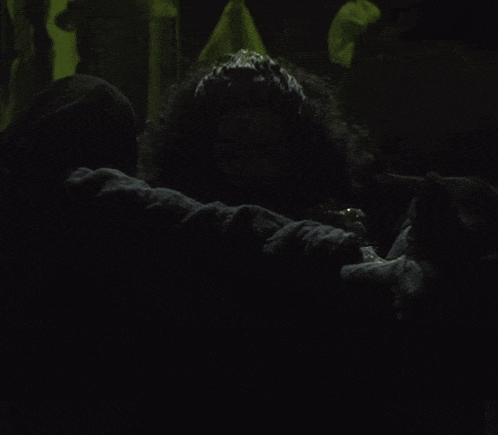 a woman with curly hair is laying on the ground in the dark