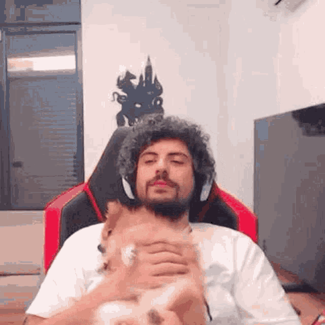 a man with headphones is holding a small dog in his lap .