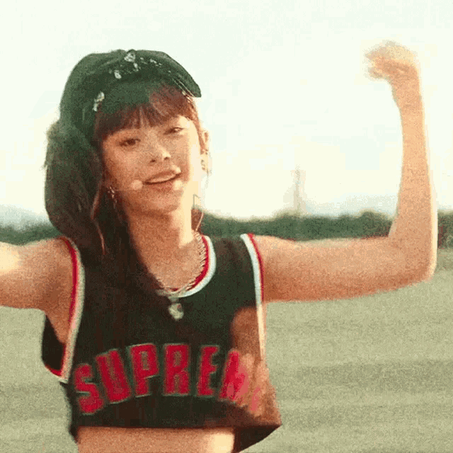 a woman wearing a black supreme crop top flexes her muscles