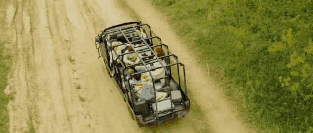 a group of people are riding in the back of a vehicle on a dirt road ..