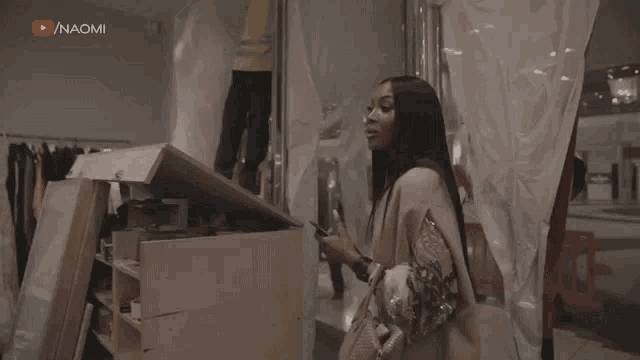 a woman standing in front of a box with the word naomi on the bottom