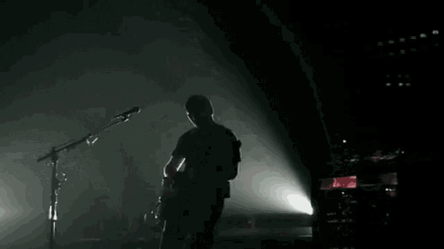a man is playing a guitar in front of a microphone on a stage .