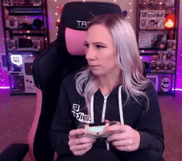 a woman is sitting in a chair holding a video game controller in her hands .