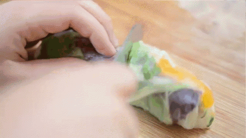 a person is cutting a piece of food with a knife on a wooden cutting board .