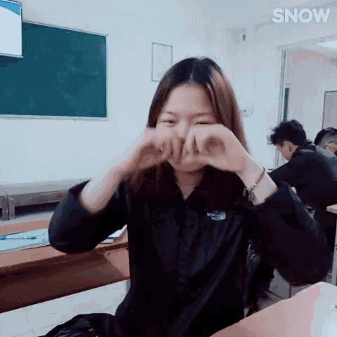a girl in a north face jacket is sitting at a desk in a classroom