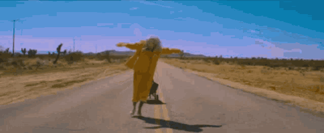 a woman in a yellow suit is walking down a road