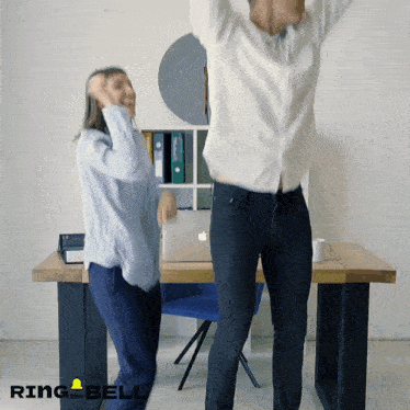 a man and woman are dancing in front of a desk with ring the bell written on the bottom