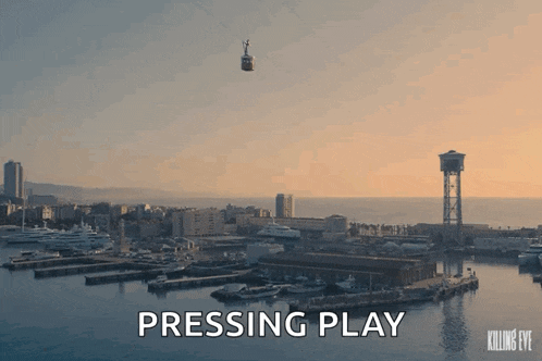 a cable car is flying over a harbor with the words pressing play below it