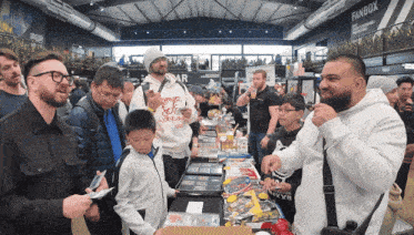 a group of people are gathered around a table with a sign that says fanbox in the background