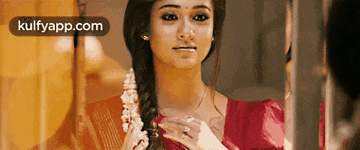 a woman in a red dress is looking at herself in a mirror with the words kulfyapp.com on the bottom