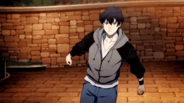 a man in a hoodie is standing on a brick floor in front of a brick wall .
