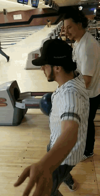 a man in a bowling alley is wearing a hat that says kansas city