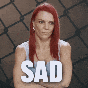 a woman with red hair is standing in front of a sad sign