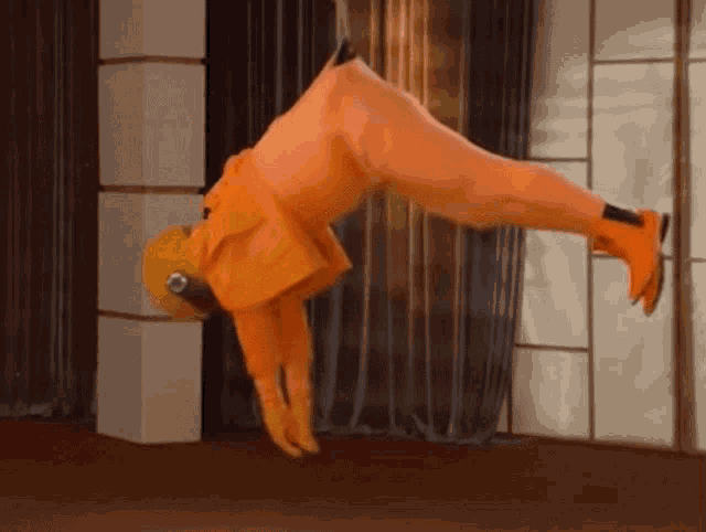 a person in an orange jumpsuit is doing a handstand