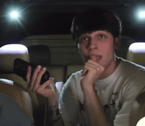 a man in a white t-shirt with a star on it is holding a cell phone in his hand