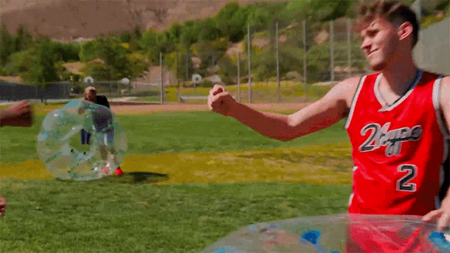 a man wearing a 2 hype jersey shakes hands with another man in a bubble soccer game
