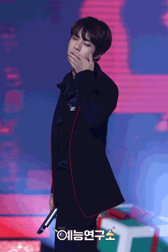 a man covering his mouth while holding a microphone in front of a sign that says ' mbc '
