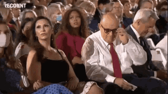 a group of people are sitting in a stadium watching a presentation .