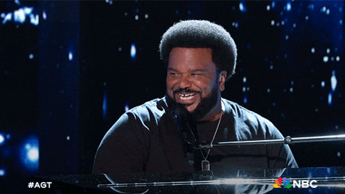 a man singing into a microphone with the nbc logo in the corner